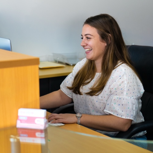 Smiling staff member at reception desk at Pink Ribbon Community Supports Australia - NDIS careers Sunshine Coast and Gympie